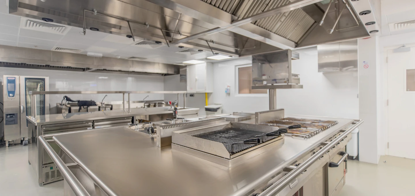 Professionellt restaurangkök med grill och stekbord skyddat av kökssläcksystem Ansulex R‑102 och ANSUL RED-detektion från A‑Sprinkler.