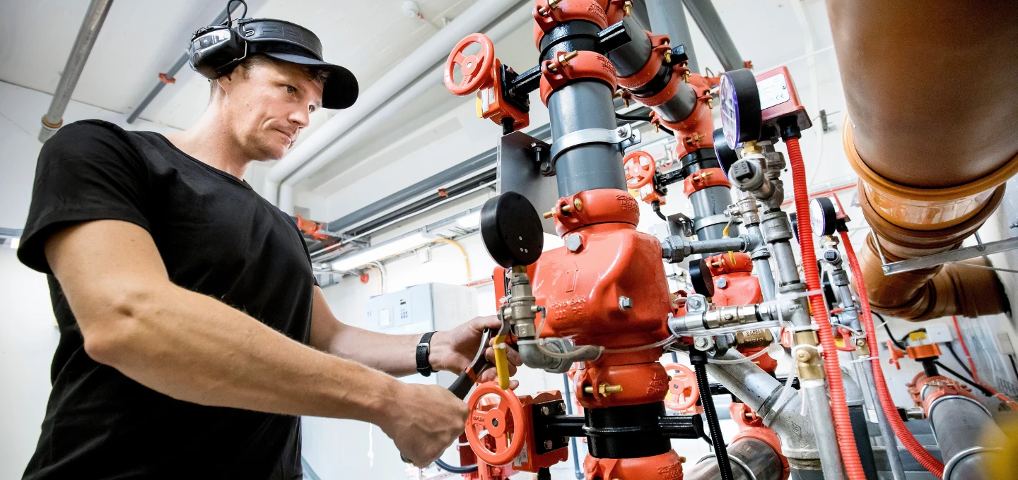 Servicetekniker som arbetar med ventiler och rör i ett sprinklersystem hos A‑Sprinkler