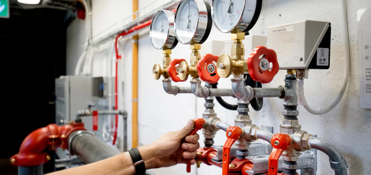 Person som utför kontroll av ventiler och tryckmätare på ett sprinklersystem under utbildning.