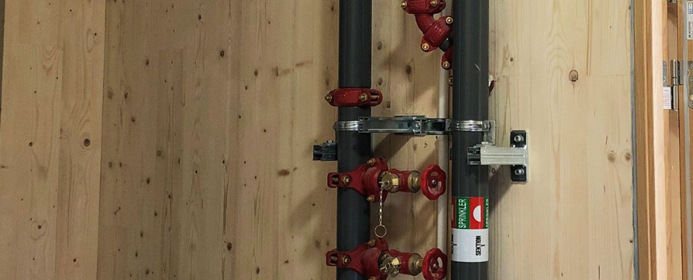 Sprinklerrör och ventiler installerade i Cederhusen som del av totalsprinklingen i träbyggnad.