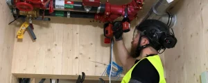 Montör installerar sprinkler i Cederhusen, en träbyggnad som totalsprinklas med våtrörssystem.