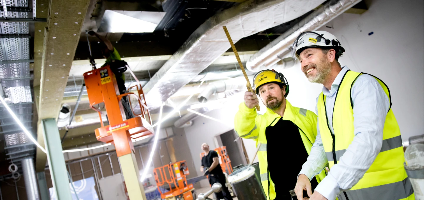 Tekniker från A‑Sprinkler som utför installationsarbete på en byggarbetsplats och planerar rördragning för brandskyddssystem.